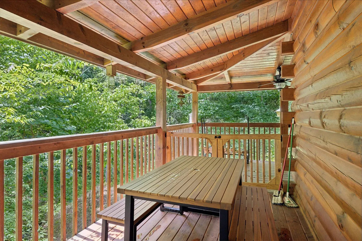 The image shows a wooden outdoor table surrounded by tall trees and open space, bathed in gentle light—possibly at sunset. The tranquil setting is ideal for outdoor dining, relaxation, and quiet moments immersed in nature.