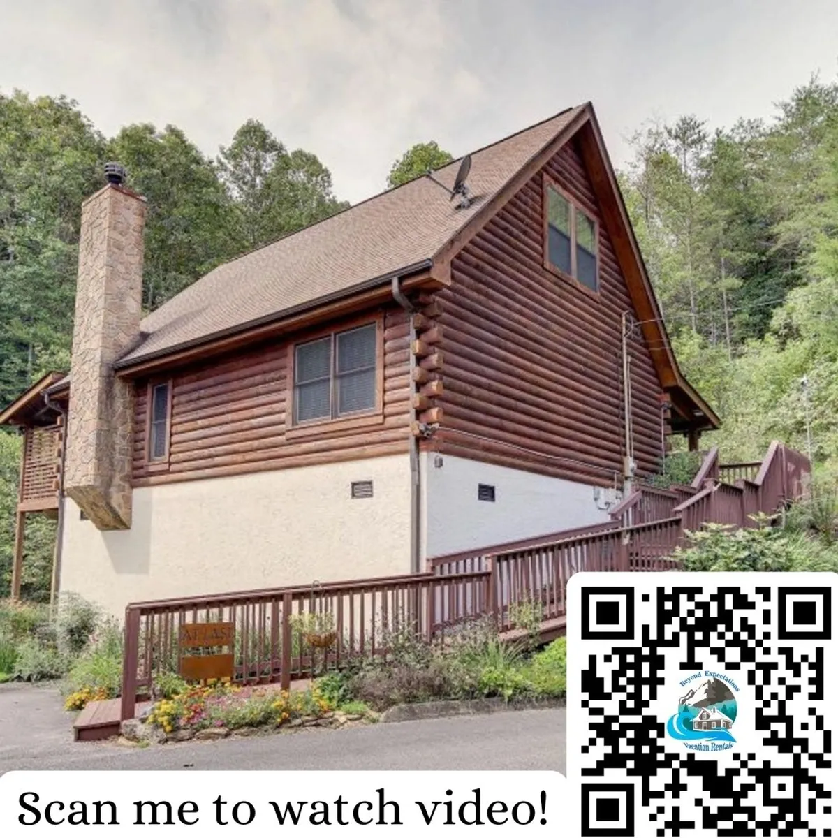The exterior of a log cabin with a stone chimney and a broad wooden deck is surrounded by landscaped gardens and lush greenery. The deck provides ample space for gatherings, morning coffee, or evening barbecues, with the landscaped lot suggesting a peaceful environment ideal for reading and family playtime.