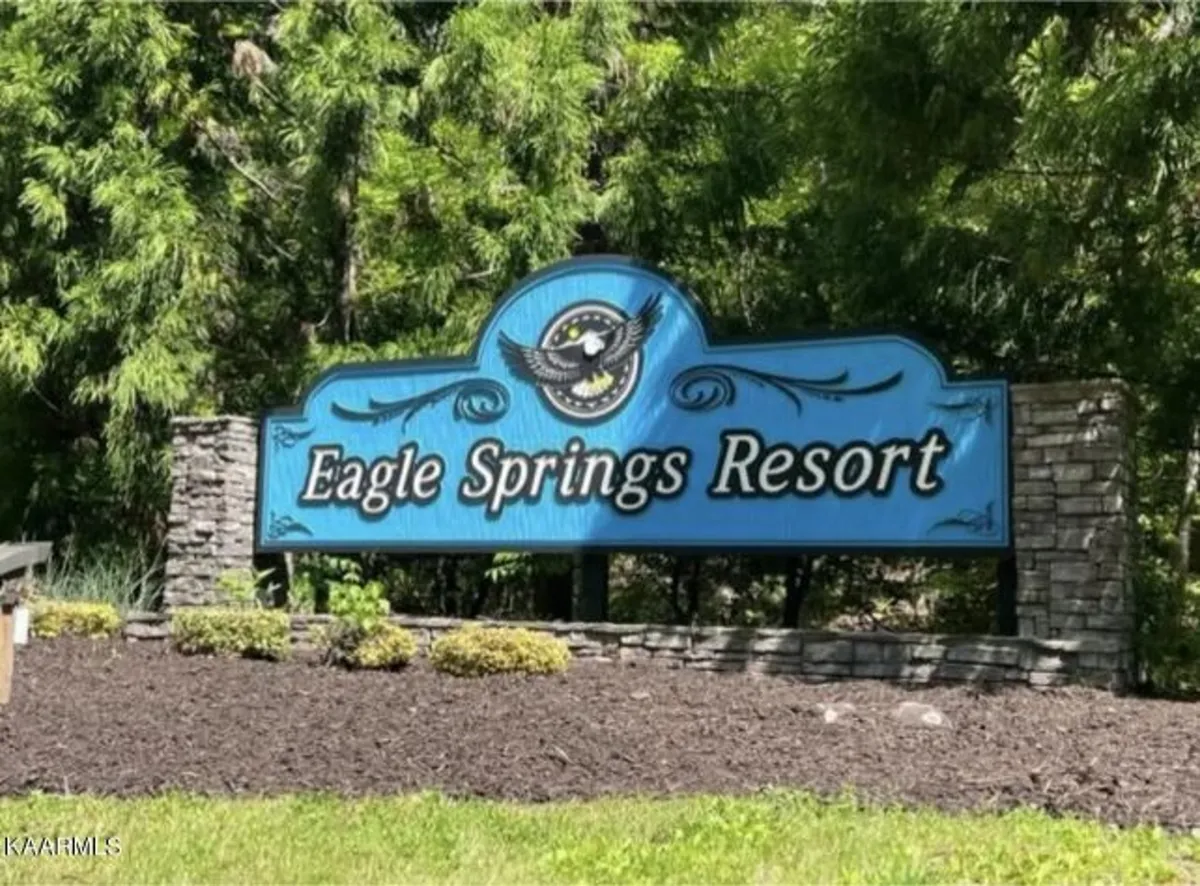 This image features the welcoming Eagle Springs Resort sign set amidst lush greenery and a stone base, capturing the inviting atmosphere of the community and its connection to the surrounding natural landscape.